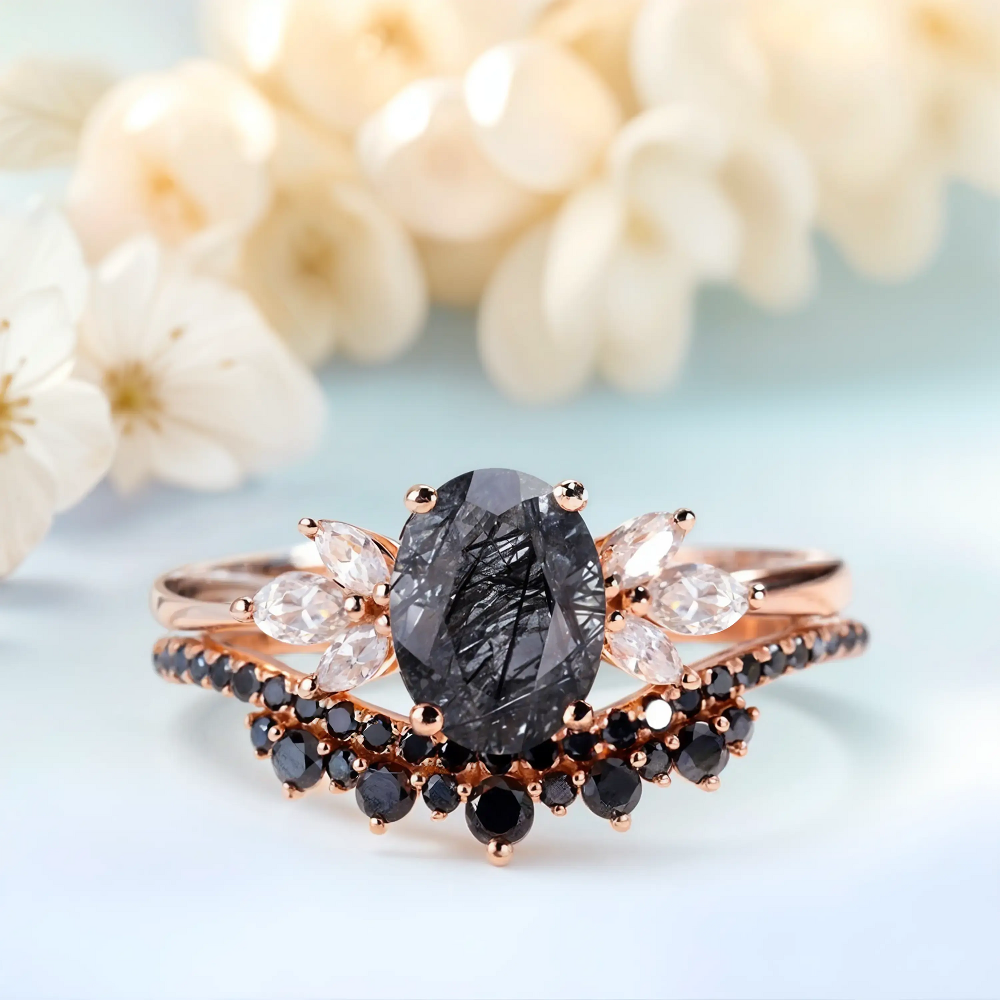 Rose gold ring with a central black gemstone and smaller diamonds on a light background