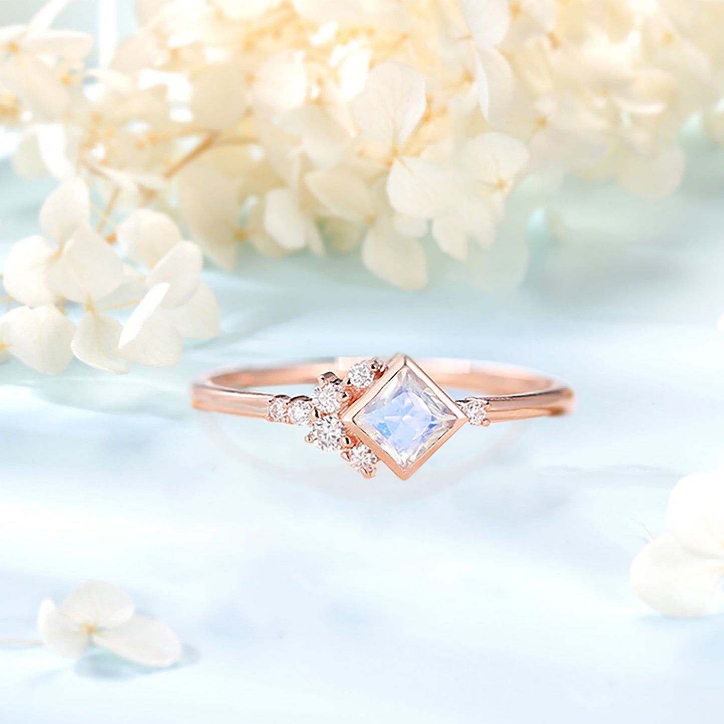 Engagement ring with a Moonstone with a white orchid on background