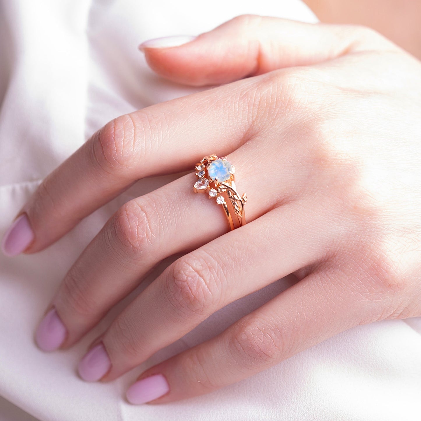 Two rings in a twig form with a Moonstone as the main stone and White Topaz as side stones on a woman hands