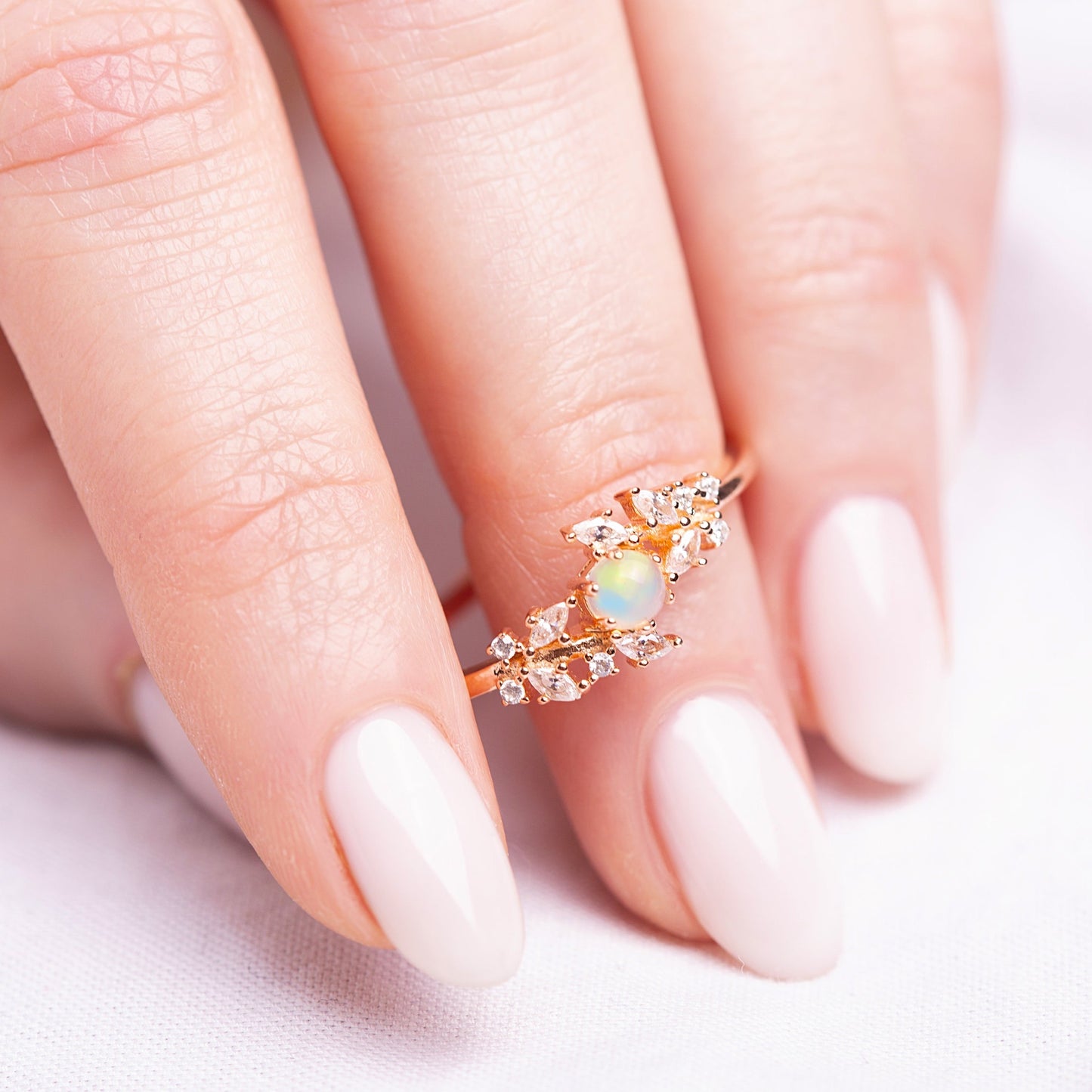 Ring with a White Opal as main stone and White Zircon in a woman hand