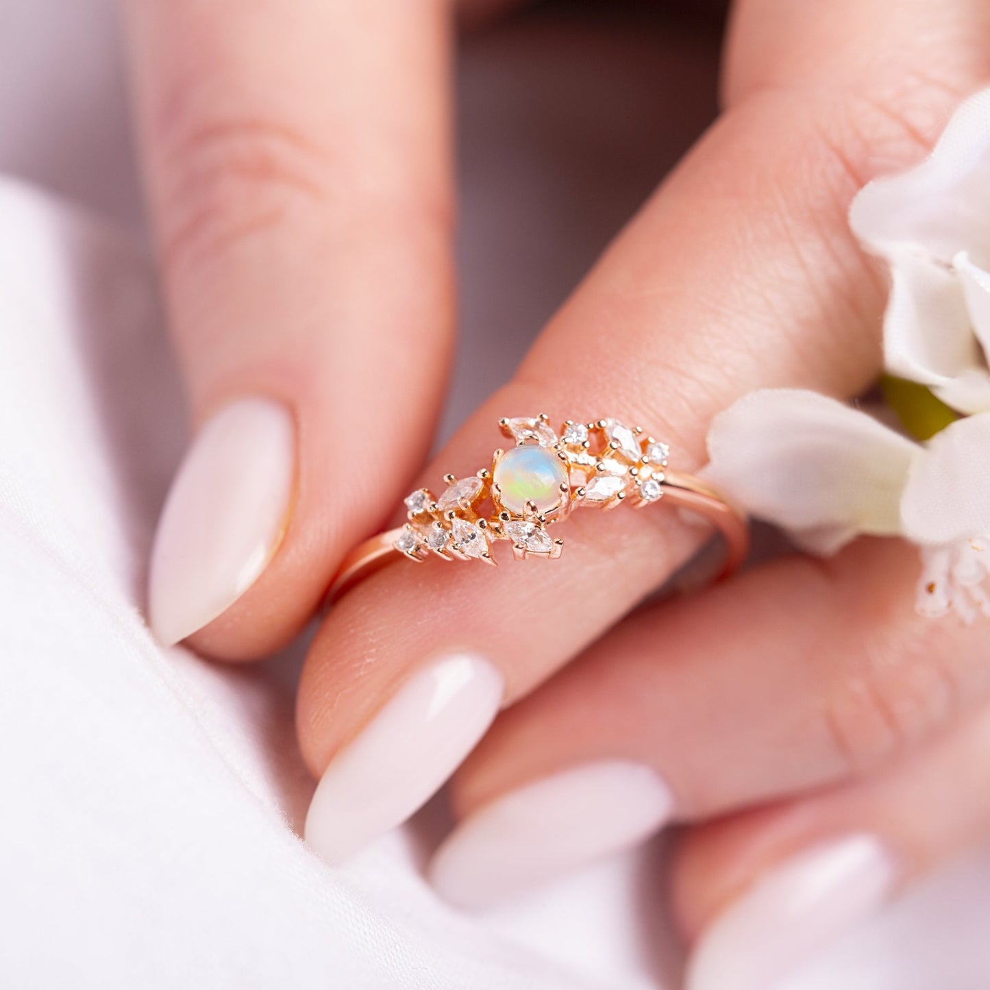 Ring with a White Opal as main stone and White Zircon in a woman hand