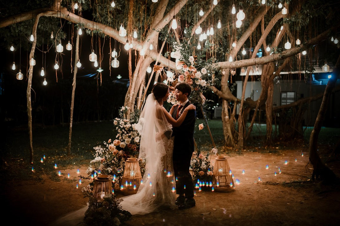 Bride and her groom dancing under lights, which hanging on a trees