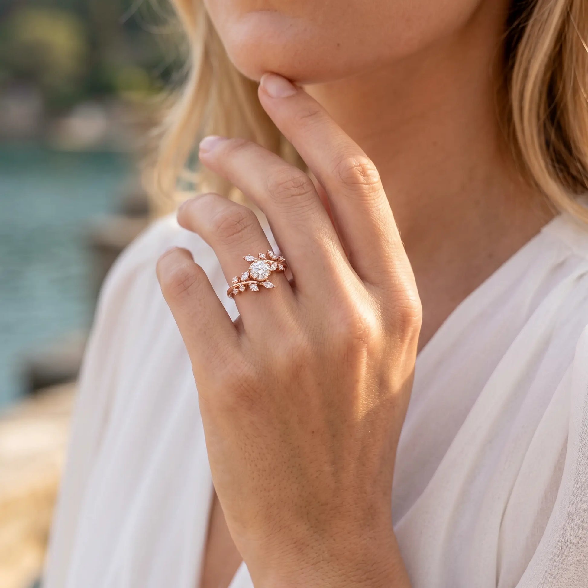Close-up of a hand wearing a rose gold ring with a diamond, outdoors.