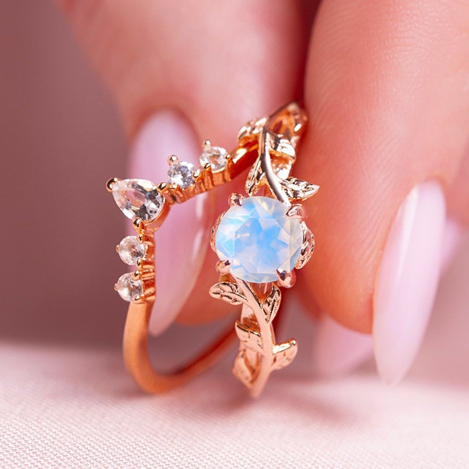 Two rings in a twig form with a Moonstone as the main stone and  White Topaz as side stones in a woman hands
