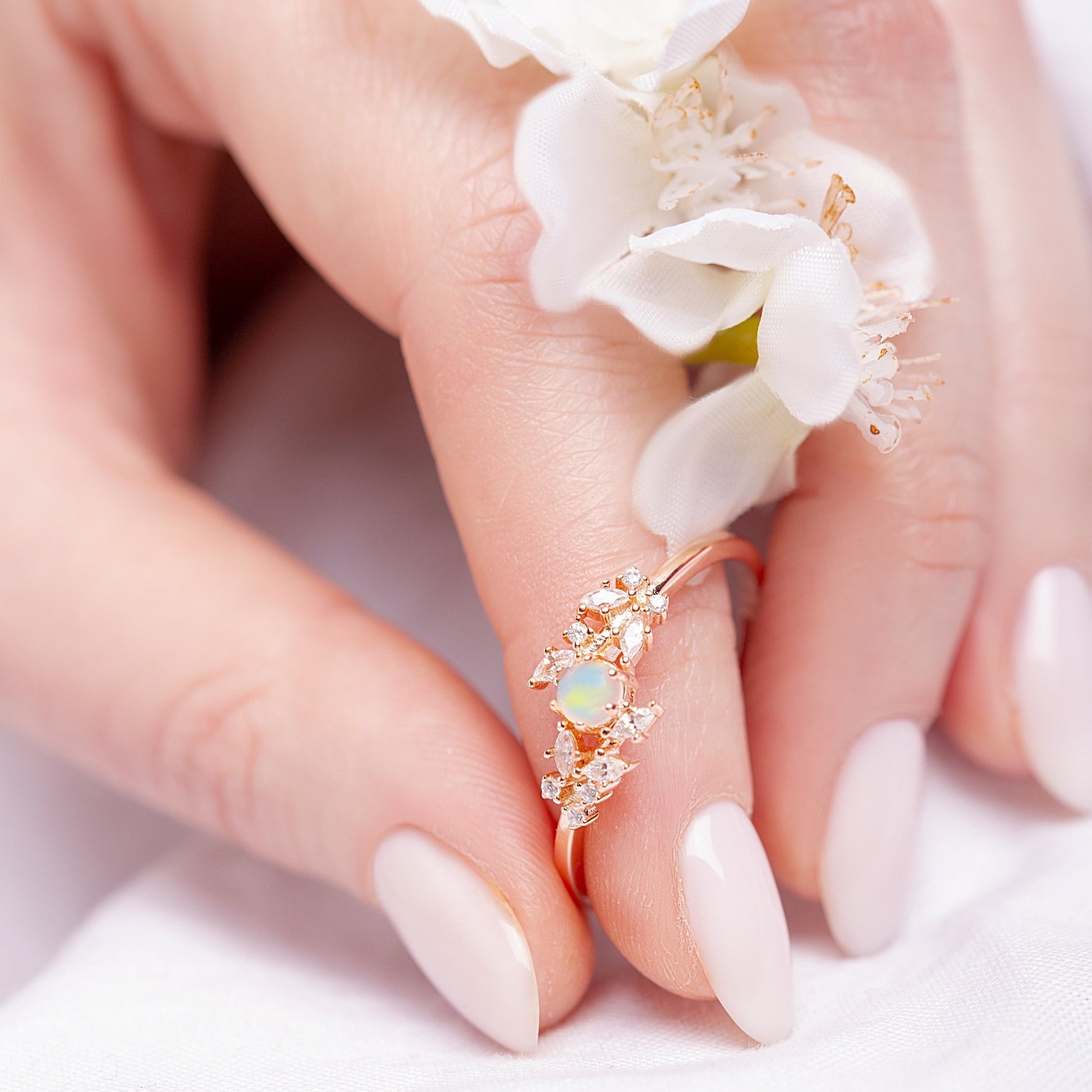 Ring with a White Opal as main stone and White Zircon in a woman hand